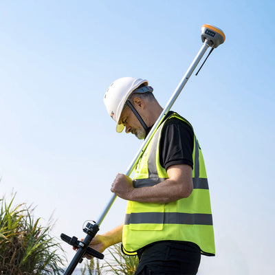 Topógrafo utilizando el receptor GNSS CHCNAV i73 IMU RTK y la controladora HCE600 en un levantamiento de campo.